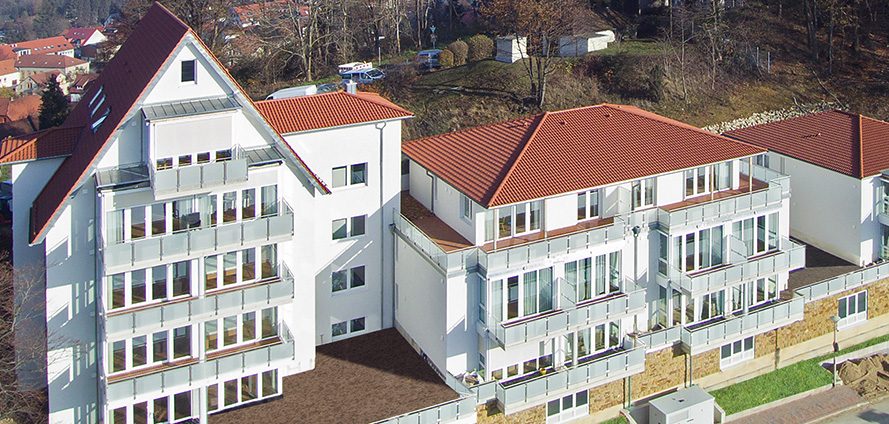 Luftaufnahme des Tönsberghauses mit drei Gebäudeteilen und roten Dächern am Waldrand