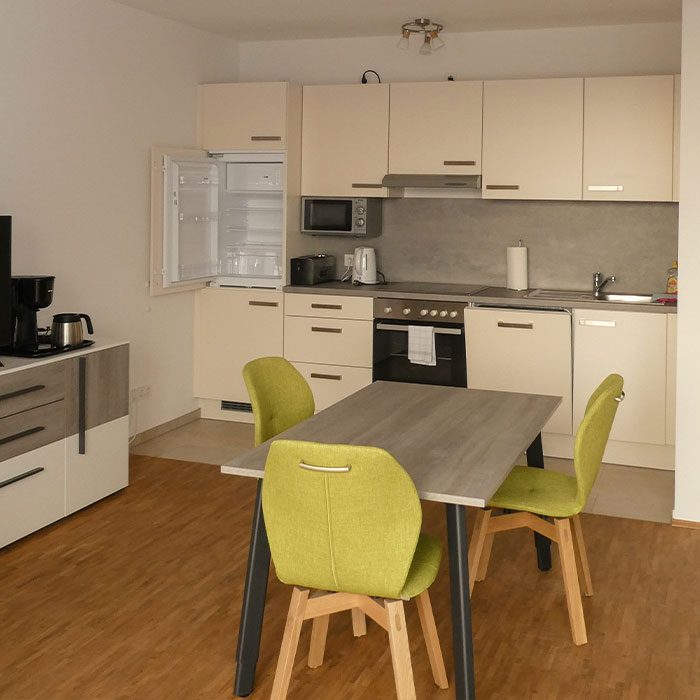 Küchenzeile mit Esstisch und grünen Stühlen in einem Appartement des Tönsberghauses